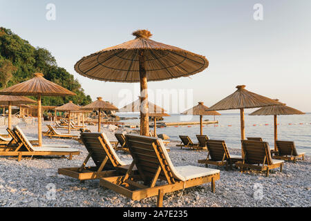 Spiaggia ghiaiosa con amache e ombrelloni al tramonto nella spiaggia di JAZ, Montenegro. Foto Stock