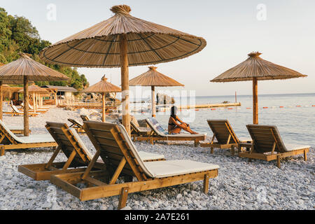 Spiaggia ghiaiosa con amache e ombrelloni al tramonto nella spiaggia di JAZ, Montenegro. Foto Stock