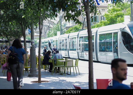 Gerusalemme, Israele - Maggio. 11, 2017: Jaffa San a Gerusalemme, la gente seduta in una caffetteria, avente la prima colazione con un leggero moderno tram in background. Foto Stock