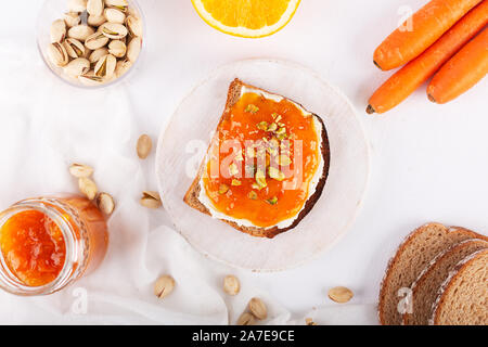 Inceppamento di carota con succo di arancia su sfondo grigio Foto Stock