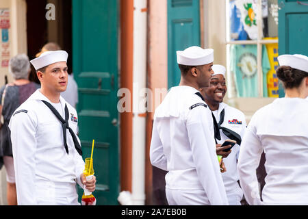 New Orleans, Stati Uniti d'America - 23 Aprile 2018: Old town street in Louisiana città con persone del gruppo dei marinai che trasportano le bevande camminando sul marciapiede durante la settimana della marina Foto Stock