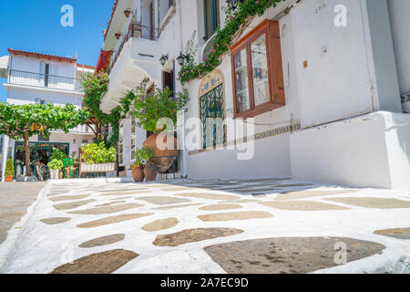 SKIATHOS GRECIA - Luglio 30 2019; Crazy pavimentazione passato leader grande terra cotta urna a sedie verdi. Foto Stock