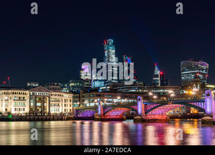 Skyline di Londra di notte illuminata inclusi ponte sul fiume Tamigi e la city di Londra in background Foto Stock