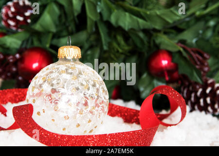 Vetro bianco baubles di Natale nella neve. Tema vacanze. Sfondo Misletoe Foto Stock