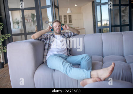 Uomo bello indossare controllato shirt ascoltando la canzone preferita Foto Stock