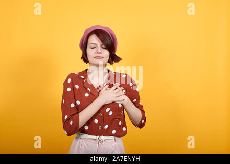 Accattivante signora con le mani sul petto gli occhi chiusi e grato gesto sul viso. Foto Stock