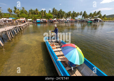 Il Vietnam Phu Quoc island 2 aprile 2019. Il vietnamita pilota di barca con un motore porta un turista con un ombrello luminoso. lo sfondo dietro di loro è un Foto Stock