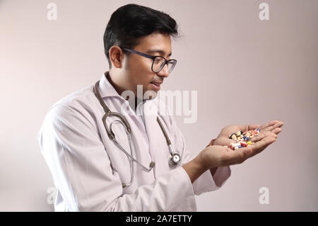 Indiano maschio medico in camice bianco e lo stetoscopio con la medicina pillole compresse capsule in mano Foto Stock