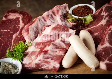 Materie di costolette e la carne di maiale o di vitello visualizzato con un assortimento di tagli di carne di manzo pronto per un barbecue adatto per la norcineria pubblicità Foto Stock