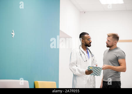 Giovane atleta consulenza con il suo medico e discutere delle prescrizioni mediche Foto Stock