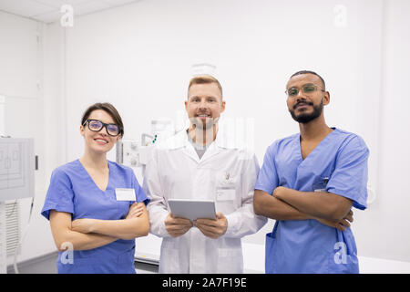 Un gruppo di tre giovani interculturale di successo ai medici o stagisti in uniforme Foto Stock