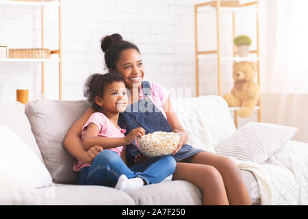 Due happy african girls watching commedia film sul televisore Foto Stock