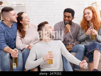 Home karaoke partito. Happy amici di cantare e bere birra Foto Stock