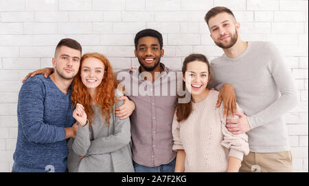 Gruppo di amici felici abbracciando e sorridente alla fotocamera Foto Stock
