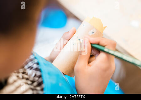 Mano del giovane contemporaneo scolaro con matita grassa faccia di disegno su carta arrotolata Foto Stock