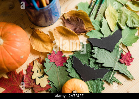 Autunno con uno sfondo colorato a secco di foglie mature, zucche e carta nera pipistrelli Foto Stock