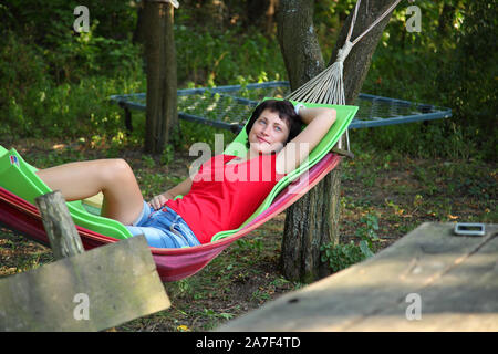 La ragazza dorme in un'amaca. La ragazza è in appoggio in una amaca nel paese. Foto Stock