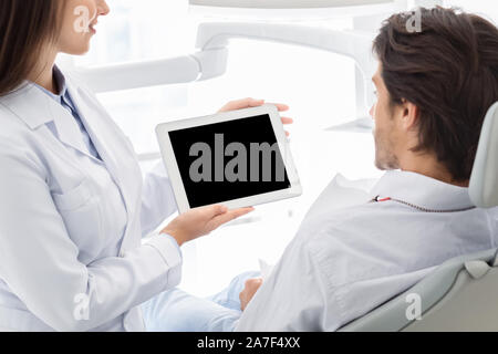 Chiusura del fustellato tavoletta digitale schermo azienda dal dentista Foto Stock