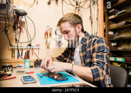 Professional repairman la piegatura su smartphone rotto ed il fissaggio di piccoli dettagli Foto Stock