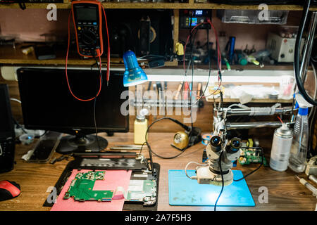 Luogo di lavoro di aggiustatore con dettagli di smontata gadget altri materiali Foto Stock