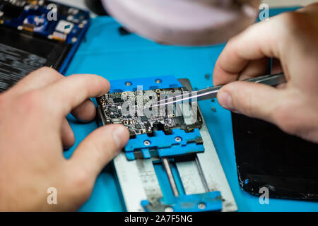 Pinzette in mani di professionisti repairman durante il lavoro con piccoli dettagli Foto Stock