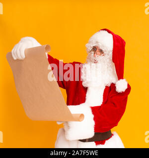 Babbo Natale lettura wishlist su sfondo arancione Foto Stock