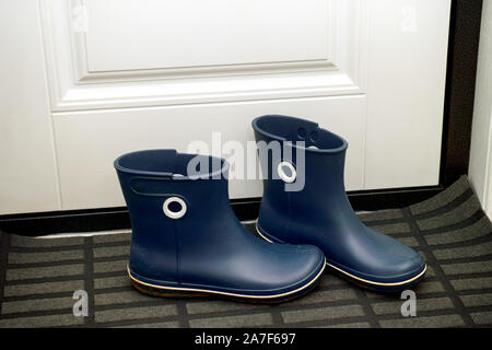 Coppie di blue stivali di gomma in piedi nel corridoio vicino alla porta. Close-up. Foto Stock