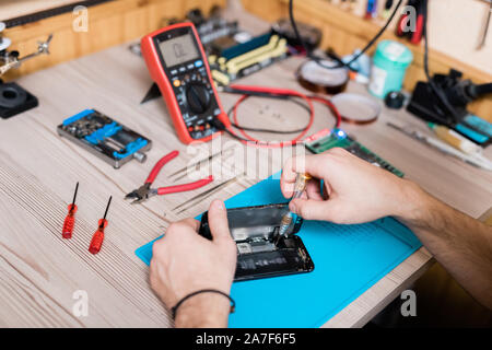 Le mani di gadget repairman fissaggio di piccoli dettagli di smartphone smontata Foto Stock