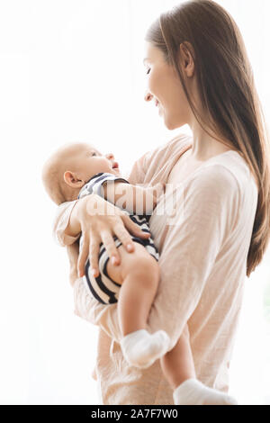 Ritratto di Madre bella lulling il suo bambino in armi Foto Stock