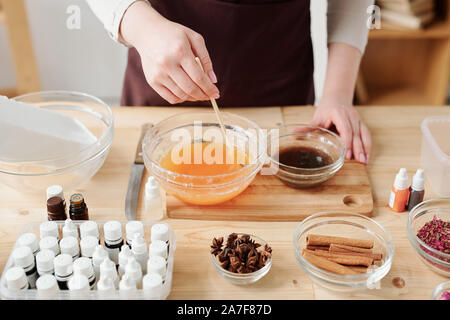 Craftswoman liquido di miscelazione la massa di sapone con olio essenziale di Arancio in vaso Foto Stock