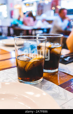 Due bicchieri di coca cola a freddo con ghiaccio e limone su un ristorante tabella Foto Stock