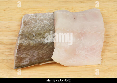Pollock i filetti di pesce su un tagliere di legno Foto Stock