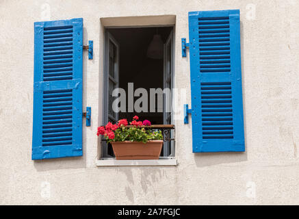 In stile tradizionale francese camera da letto finestra con persiane blu e gerani in una finestra Foto Stock