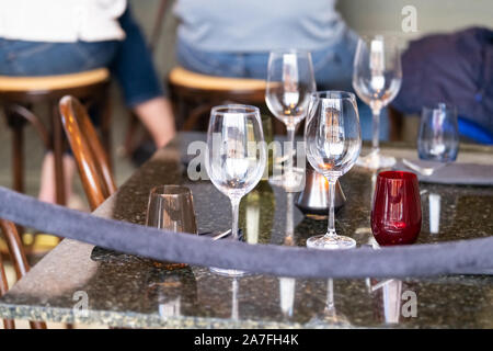 Il vino di cristallo bicchieri di vetro sul ristorante tavolo esterno su street cafe con persone di background in New Orleans, Louisiana Foto Stock