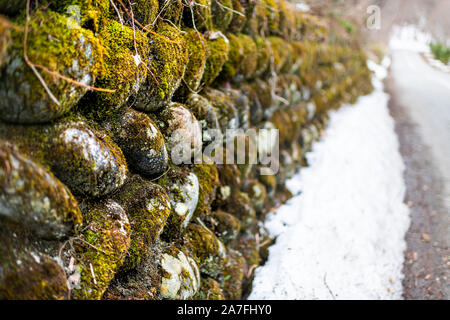 Abstract closeup di muro di pietra in Okuhida villaggi vicino a Takayama, Giappone montagna nella Prefettura di Gifu park con MOSS e neve su strada Foto Stock