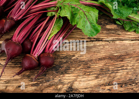 Organici di barbabietole con herbage foglie verdi su una tavola in legno rustico con spazio di copia Foto Stock