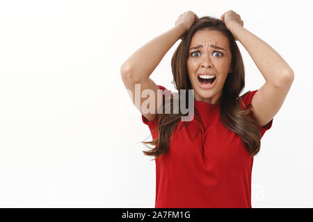 Remourse, il dolore e il fallimento del concetto. Sconvolto sconvolto nel panico brunette woman in red t-shirt tirare capelli fuori di testa, urlo deluso, bloccata in Foto Stock