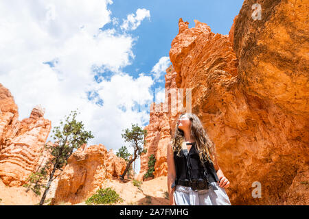 Giovane donna in piedi guardando il paesaggio del deserto vista estiva nel Parco Nazionale di Bryce Canyon su loop Navajo ampio angolo con la fotocamera e il cielo Foto Stock