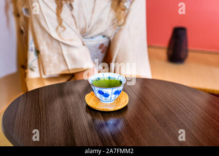 Tradizionale donna giapponese in kimono seduta in costume da alcova pensile scorrimento carta di bere il tè verde nella cerimonia Foto Stock