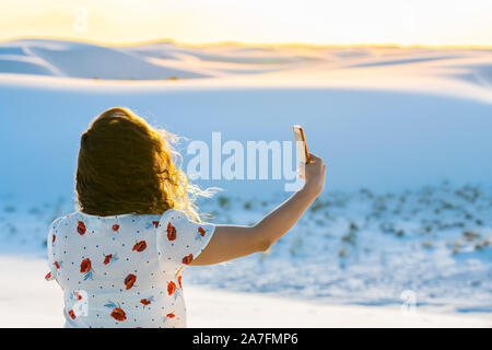 Donna closeup tenendo selfie foto in bianco dune di sabbia monumento nazionale nel Nuovo Messico usando il telefono con il vento Foto Stock