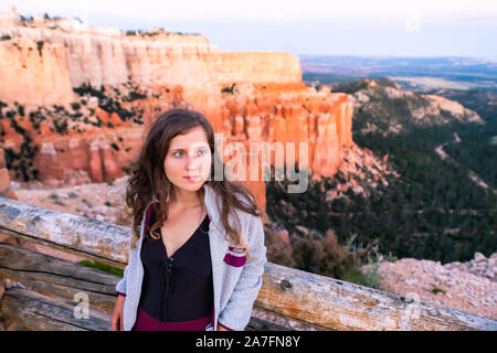 Giovane donna alla vista di Paria si affacciano con il tramonto hoodoos formazioni rocciose nel Parco Nazionale di Bryce Canyon appoggiata sul parapetto Foto Stock