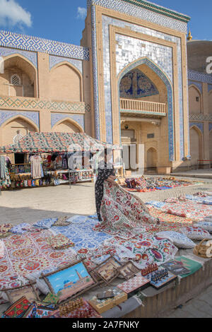 Commerciante al di fuori dell'islam khoja madrassa in ichan kala o città interna di Khiva uzbekistan Foto Stock