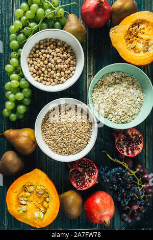 Autunnale di frutta e cereali sani sfondo, frutto tipico della stagione autunnale, coltivati biologicamente, arrotondamento ciotole piene di sano cereali di avena Foto Stock