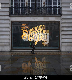 Il 2 novembre 2019. Superdry store window con scritte in oro riflettendo sul pavimento bagnato in autunno meteo di Regent Street, Londra, Regno Unito. Foto Stock