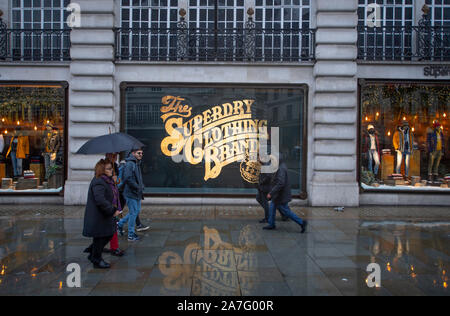 Il 2 novembre 2019. Superdry store window con scritte in oro riflettendo sul pavimento bagnato in autunno meteo di Regent Street, Londra, Regno Unito. Foto Stock