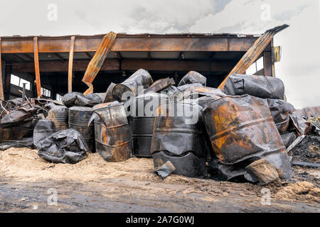 Bruciato carbonizzato barili di olio motore sullo sfondo del magazzino bruciato. vista dopo il fuoco Foto Stock