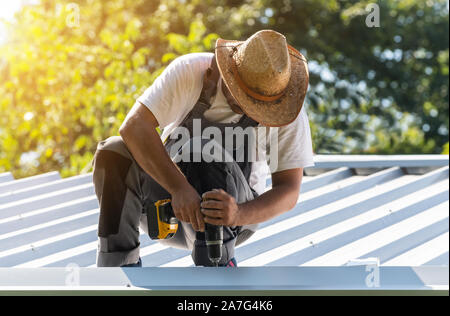 Copritetti lavoratore edile lavora in un cantiere. Foto Stock