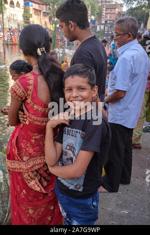 Un ragazzo con la sua famiglia la famiglia a Banganga serbatoio, Walkeshwar, Mumbai, India, frequentando festival Chhath Puja, che onora Suryadev il dio del sole Foto Stock