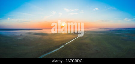 Un magnifico panorama del campo bielorussi al mattino all'alba con nebbia e un fiume. Splendido sole che va al di fuori dell'orizzonte. Vista aerea Foto Stock