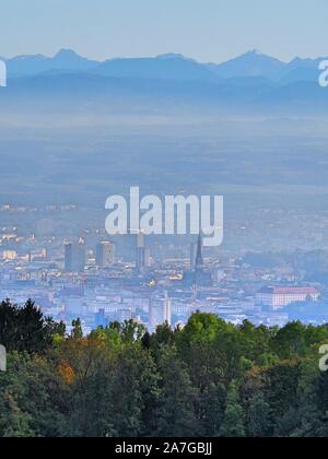 La città di Linz dalla parte superiore su un vago giornata d'autunno. Forest, Natura urbana della città e delle montagne sullo sfondo Foto Stock